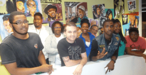 A group of people standing in front of some pictures.