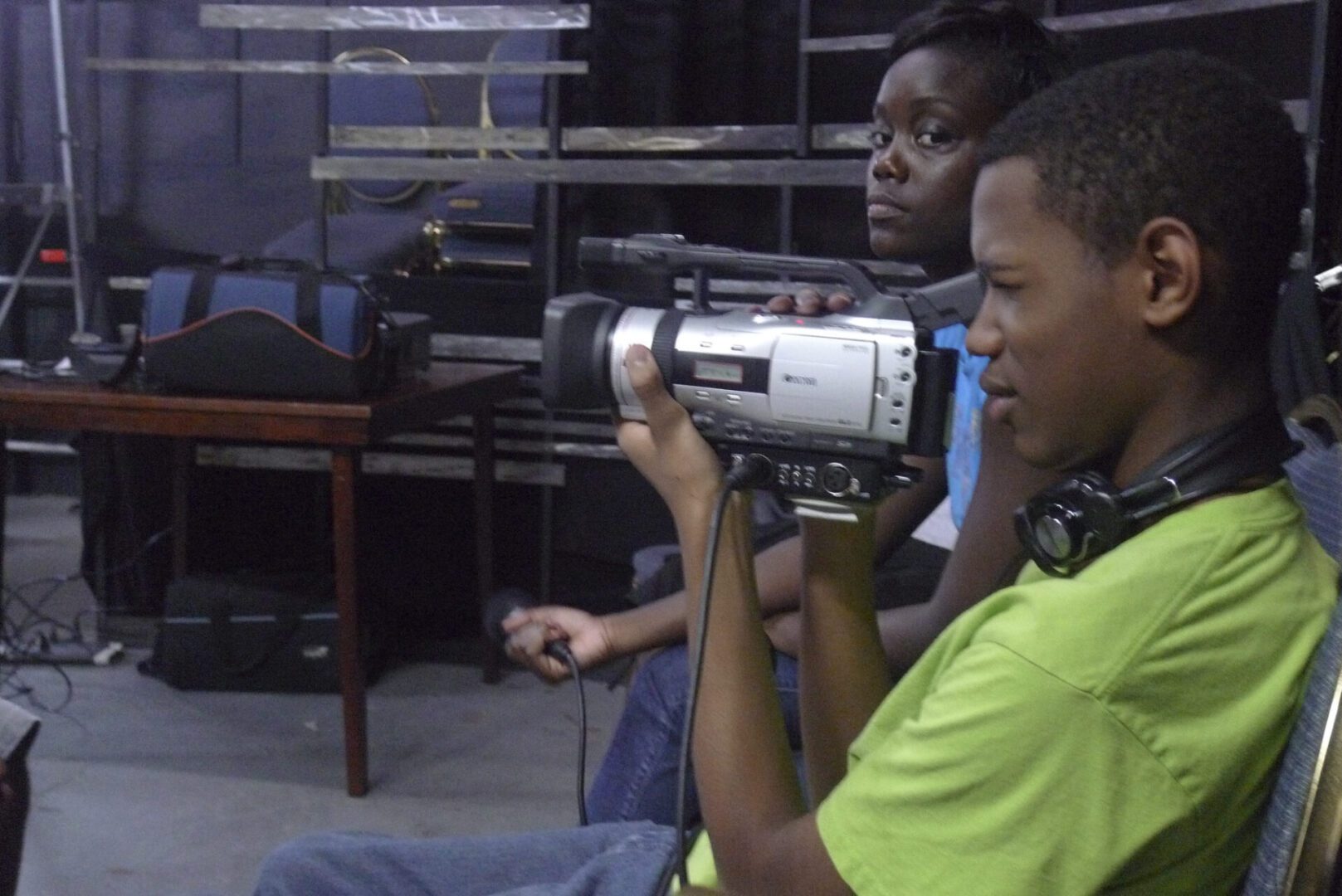 Two young men are watching a video camera.