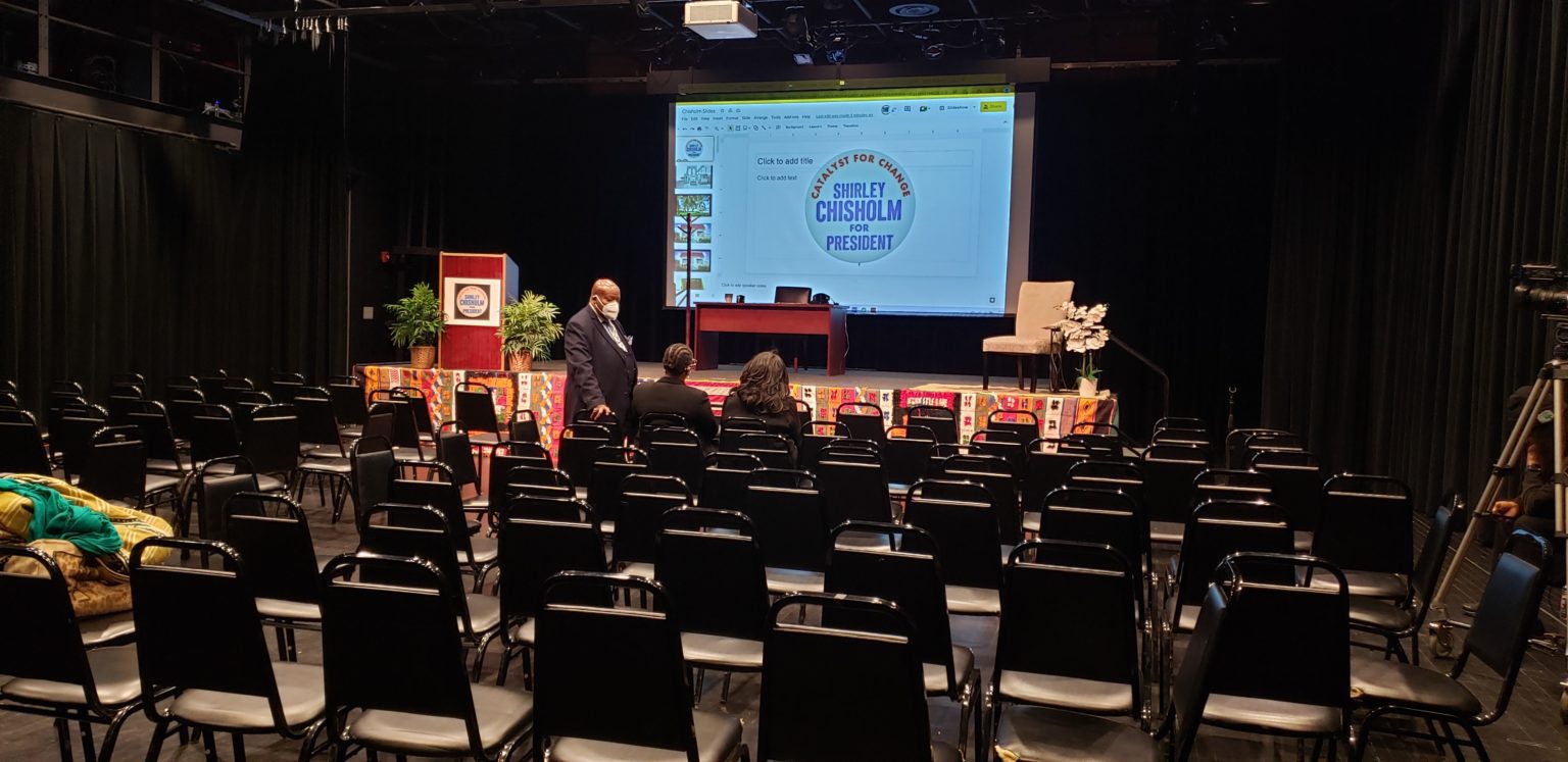 A large screen in front of many chairs.