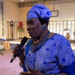 A woman in blue is holding a microphone