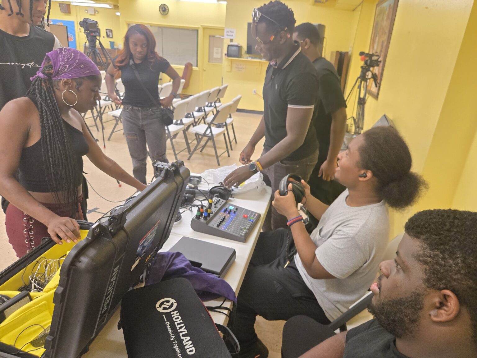 Youth media student preparing technical equipment for event production, managing lighting and sound systems during hands-on media training.”