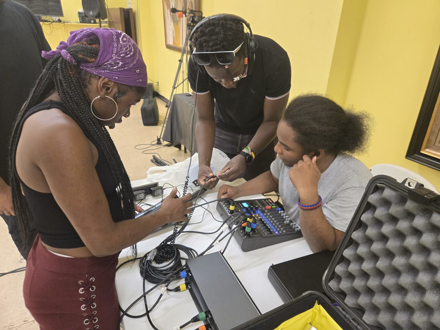 Youth media student preparing technical equipment for event production, managing lighting and sound systems during hands-on experience on media training.”